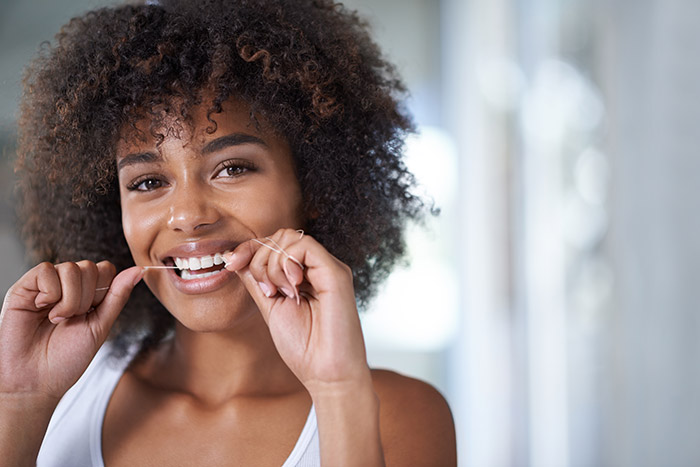 A girl cleaning her teeth with thread