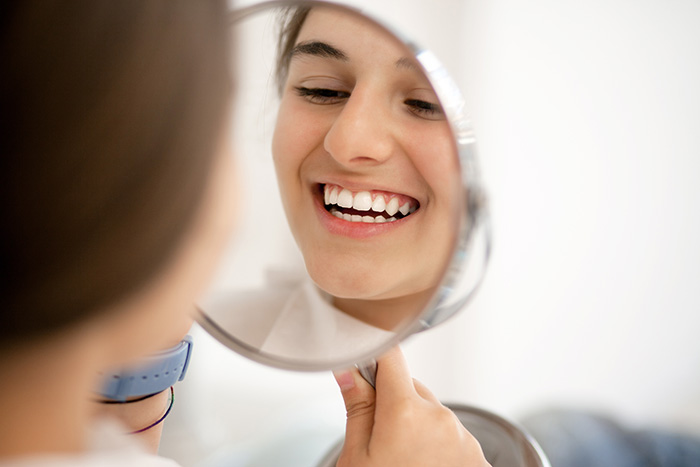 A girl looking at her teeth in mirror